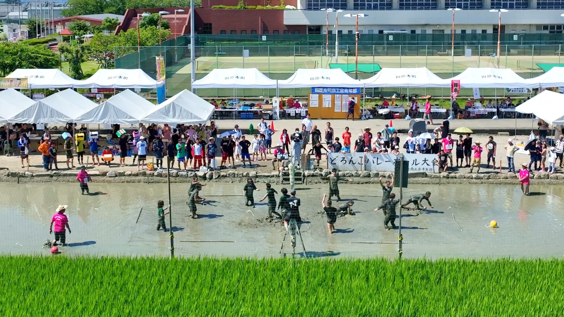 Players competing in the Tawaramoto mud volleyball tournament in rice paddies